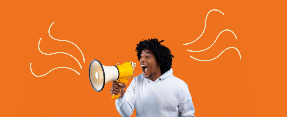 Fundo laranja. Homem negro com cabelo black power e blusa de frio branca. Ele está comum megafone nas mãos